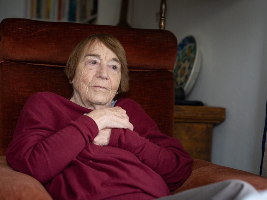 Renate Welsh sitzt mit verschränkten Armen in einem roten Lehnsessel