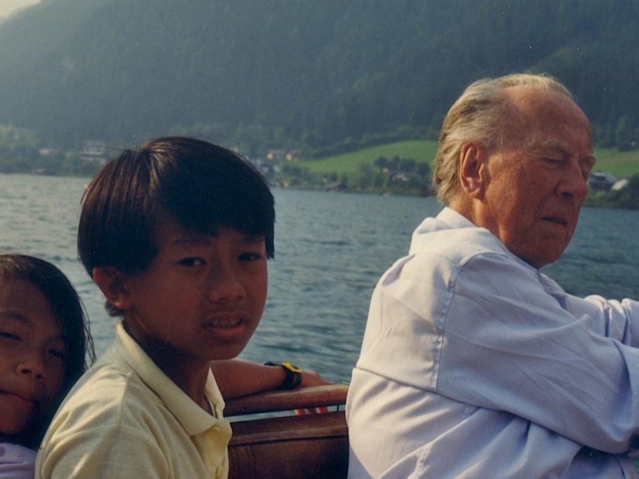 Ein älterer Mann, Kardinal König, sitzt auf einem Boot, neben ihm zwei vietnamesische Kinder mit neugierigen Blicken.