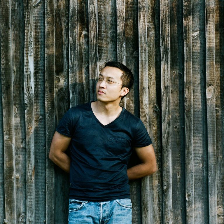 Regisseur Martin Nguyen steht vor einer Holzwand